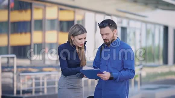 商务女士告诉一位同事会计文件中需要更正什么这位女士拿着一台移动电话视频的预览图
