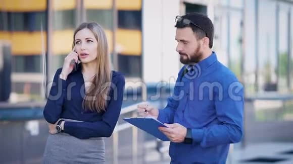 女商人和她的助手正在用手机和一个大投资者在街上交谈那人做笔记视频的预览图