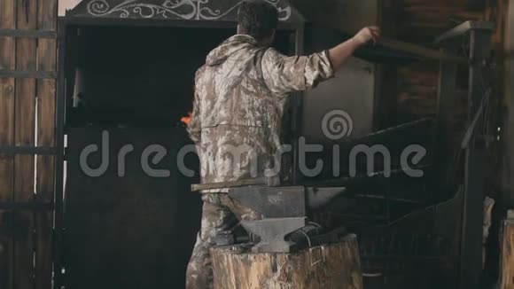 大胡子铁匠在室内用空气燃烧着原始的锻造壁炉视频的预览图