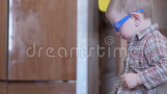 可爱的男孩戴着滑稽的眼镜两只手在家里用纸画画视频的预览图
