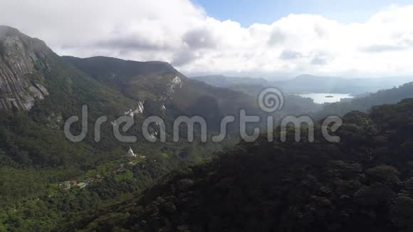 从空中俯瞰亚当峰的树木茂密的山脉以及它们之间在斯里兰卡的聚落视频的预览图