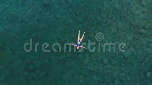 空中漂浮在蓝色水面上的女人在透明的地中海游泳从上往下看夏季度假视频的预览图