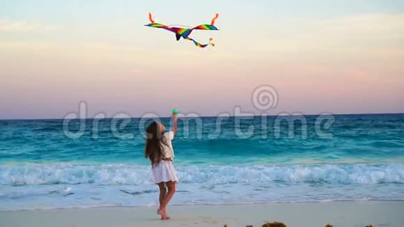 可爱的小女孩在热带海滩放风筝快乐的孩子在海边玩海滩风筝缓慢移动视频的预览图
