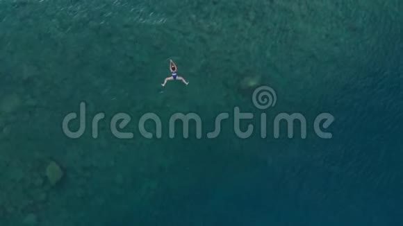 女孩漂浮在蓝色水面上的女人在透明的地中海游泳从上往下看夏季度假视频的预览图