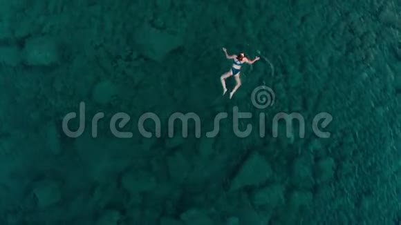 空中慢动作女人漂浮在蓝色水面上在透明的地中海游泳俯视夏季度假视频的预览图
