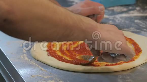 厨师在意大利披萨上抹番茄酱视频的预览图