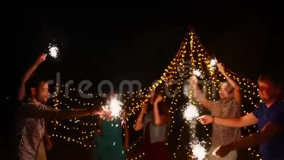 年轻人在晚上的海滩聚会上用火花跳舞视频的预览图