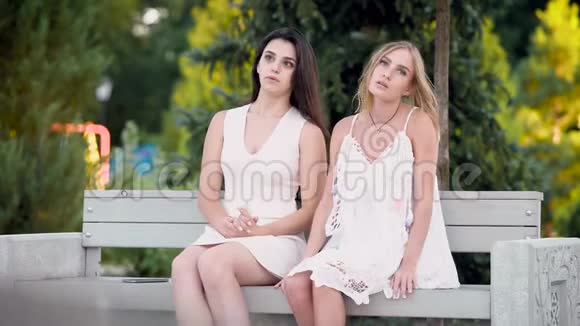 两个好朋友正在公园的长椅上谈心穿白色衣服的女孩讨论视频的预览图