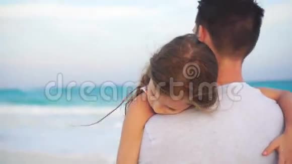 父亲和他可爱的小女儿在白色海滩一家人在海边夕阳下散步视频的预览图
