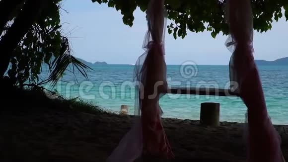 在树下和海滩上的拱门下举行婚礼的绳子秋千视频的预览图