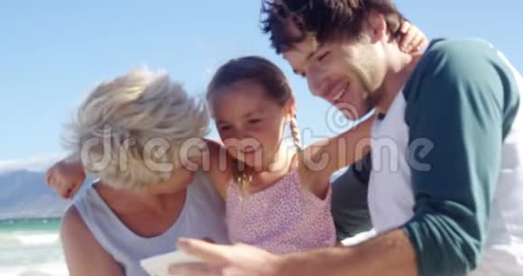 多代家庭在海滩上使用手机视频的预览图