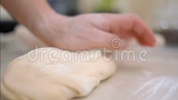 在厨房里用面粉面包师双手揉搓桌子上的面团视频的预览图