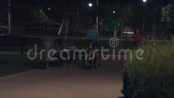 两个孩子晚上在公园里骑自行车视频的预览图