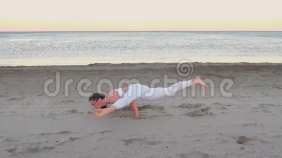 日出时在沙滩上做瑜伽的年轻女子平衡姿势视频的预览图