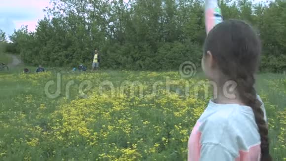 一个穿灰色衣服的年轻女子穿过花田向她的朋友挥手女孩向一群游客朋友挥手视频的预览图