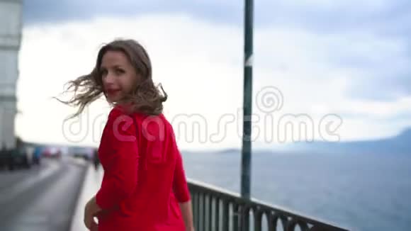 穿着红裙子的女人沿着海滨奔跑视频的预览图