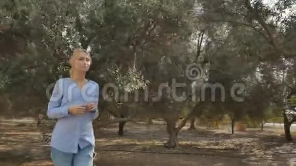 美丽的姑娘带着橄榄树沿着种植园散步视频的预览图