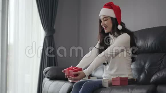 惊喜的女士在客厅打开圣诞礼物视频的预览图