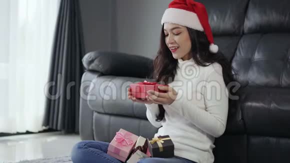惊喜的女士在客厅打开圣诞礼物视频的预览图