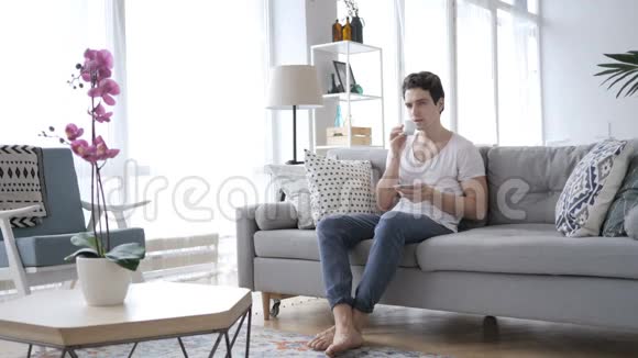 男人一边喝咖啡一边坐在沙发上视频的预览图
