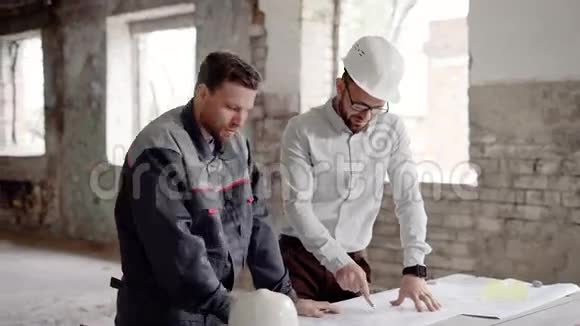 一个头戴头盔的商人和一个正在讨论建筑蓝图的专业建筑工人视频的预览图