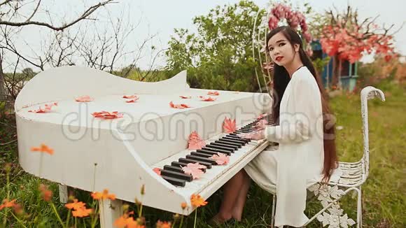 越南女孩留着长长的黑发在户外弹钢琴秋天的主题枫叶散落在钥匙上视频的预览图