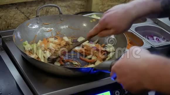 厨师用木铲混合油炸原料视频的预览图