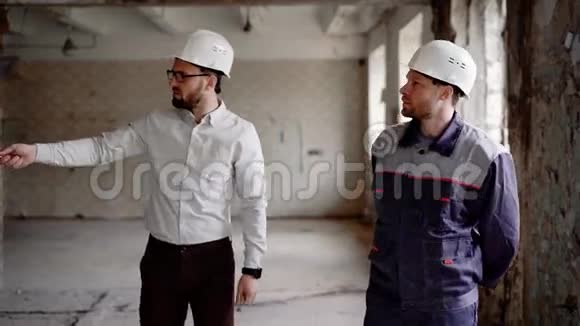 一个头戴头盔的商人和一个穿着防护制服的建筑主管正在考虑视频的预览图