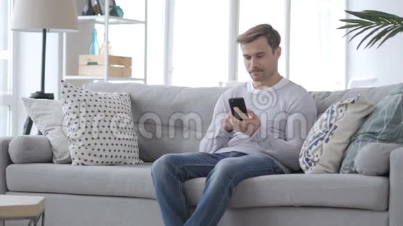 坐在沙发上用智能手机的成年人视频的预览图