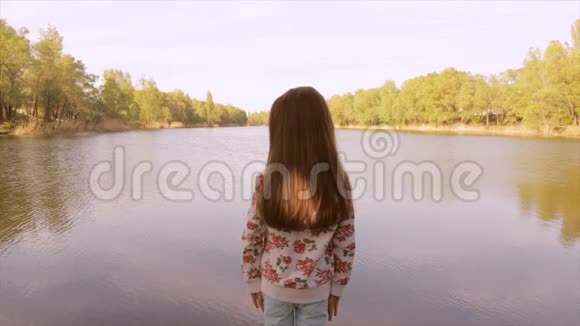 3女孩用双手托着腰看着湖视频的预览图