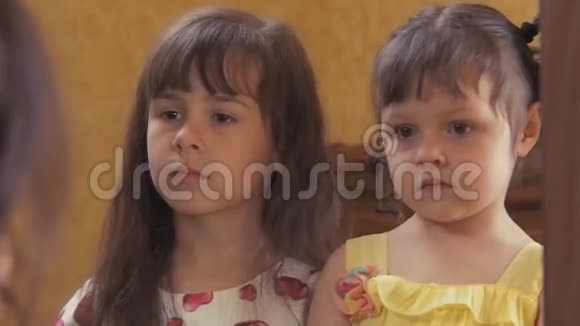 小女孩在照镜子两个姐妹嘲笑他们的想法镜子旁美丽的孩子视频的预览图