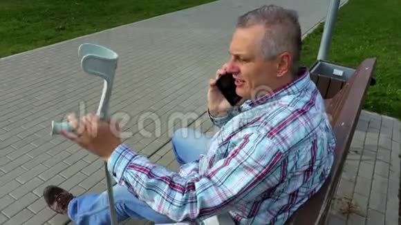 残疾人坐在长椅上使用智能手机视频的预览图