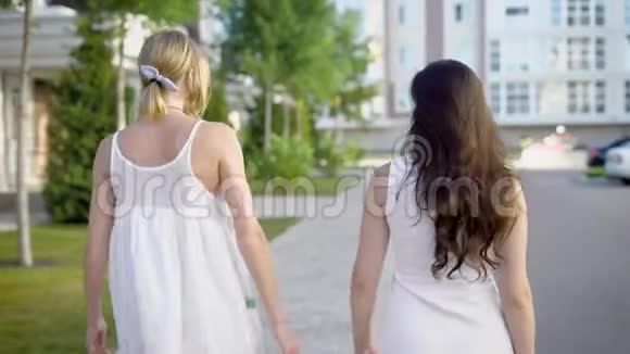 两个穿着白色连衣裙的漂亮女人走在小巷里兴高采烈地谈论着一些事情视频的预览图