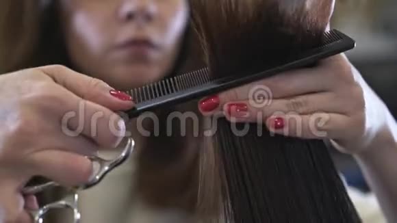 年轻的面目全非的理发师剪着她客户的深色长发视频的预览图