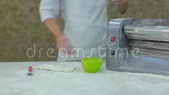 在白色衣服里用机器擀面团把厨师的双手紧紧地握起来视频的预览图