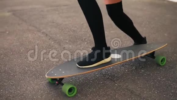 在城市的道路上黑色运动鞋滑板的女人的腿的特写滑板上的腿慢动作视频的预览图