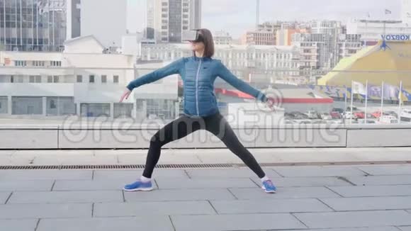 女性在城市背景下进行瑜伽健身运动在办公楼内佩戴虚拟现实耳机视频的预览图