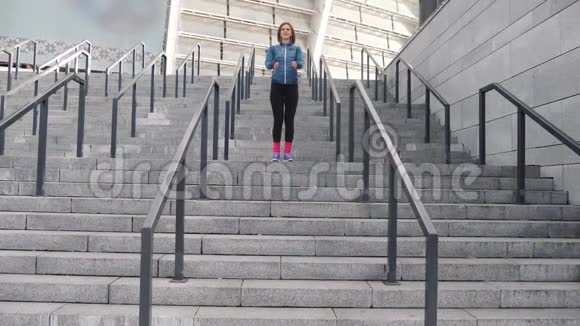 女孩跳楼梯在城市户外健身锻炼耳机听音乐健康生活方式视频的预览图