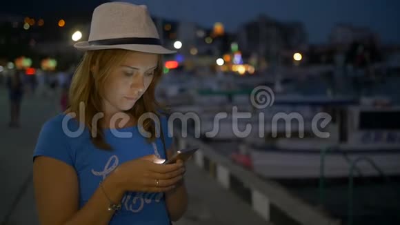 年轻女孩在后台夜空的手机上写信视频的预览图