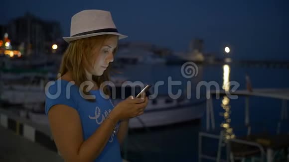 年轻女孩在后台夜空的手机上写信视频的预览图