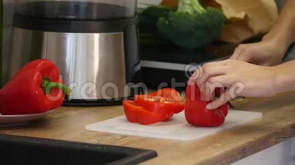 女人手在木切割板上切甜的红钟胡椒健康食品概念视频的预览图