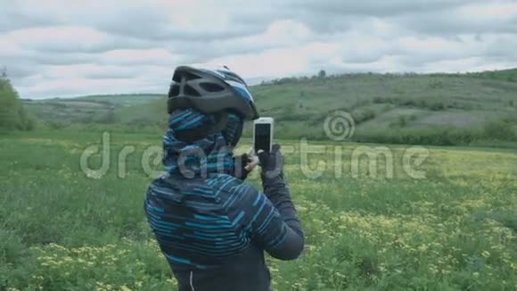 一个戴着头盔的年轻女人拍摄智能手机的性质视频的预览图