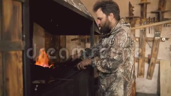 大胡子的年轻人铁匠准备生火在室内的铁匠作坊里干活视频的预览图