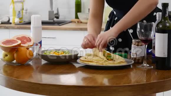 女人的手紧紧地在煎饼上放馅在木制圆桌上烹制国家美食视频的预览图