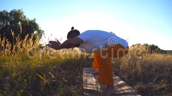 年轻人在草地上练习瑜伽动作和姿势在阳光明媚的日子里在球场上训练运动男视频的预览图