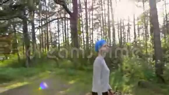 穿着蓝色头巾在森林里行走的白种人美女身后太阳耀斑视频的预览图
