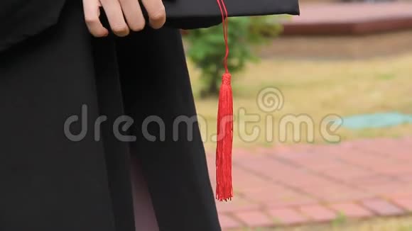 毕业日女学生身穿长袍手拿流苏戴着学术帽视频的预览图