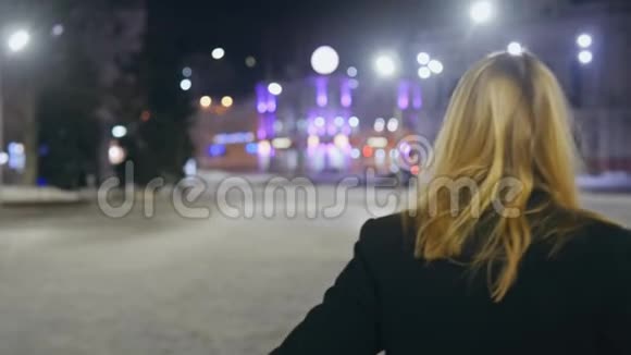 年轻的金发女郎走在夜街上享受生活夜晚的城市有博克灯视频的预览图