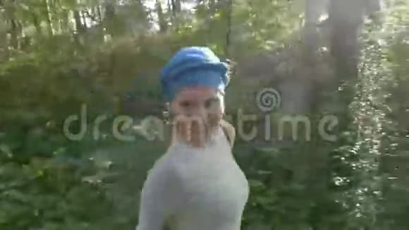 戴着头巾的快乐女人在森林上空的绿草上奔跑慢镜头视频视频的预览图