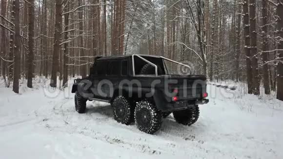 越野车6x6站在冬季森林积雪的道路上鸟瞰视频的预览图
